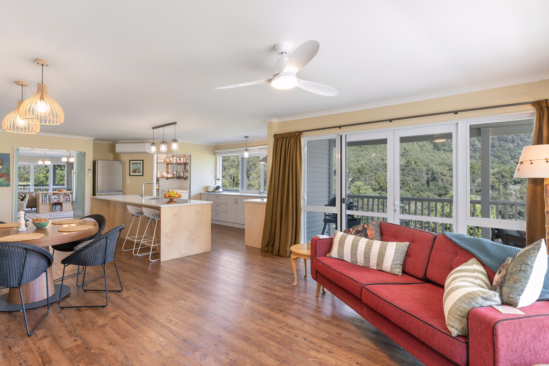 Open-plan living and dining space opening onto native bush